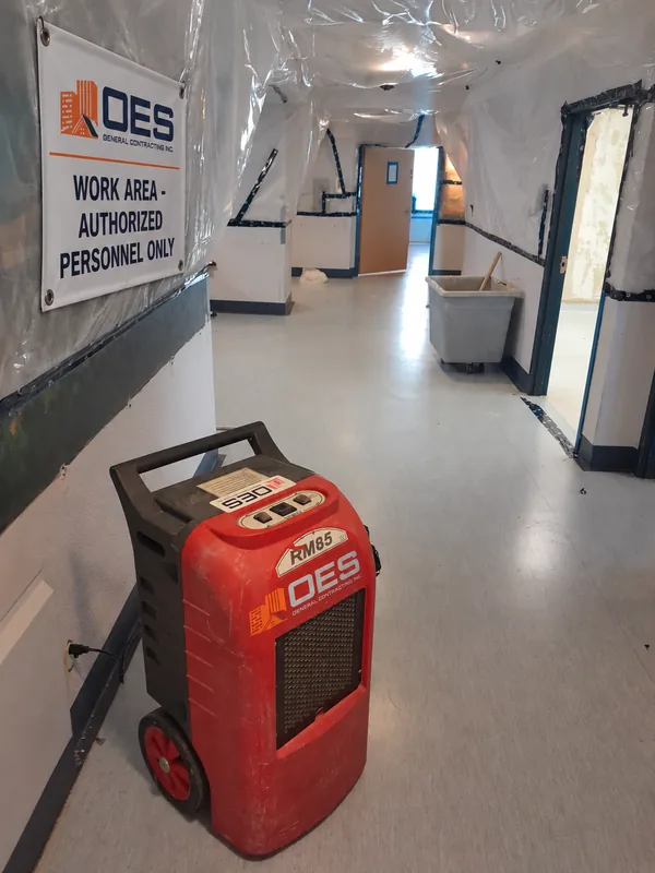 Dehumidifier running in a corridor sealed with plastic sheeting