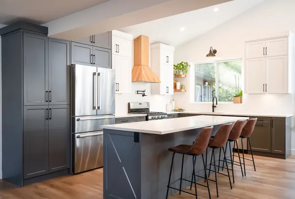 Kitchen with dark blue cabinets, a quartz island and a wood range hood