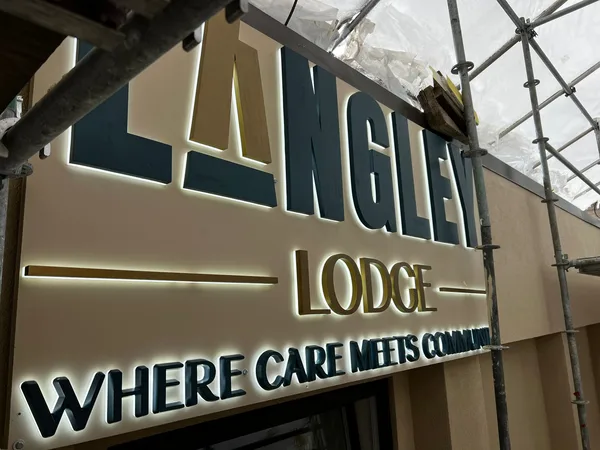 Lit Langley Lodge sign under scaffolding and weather sheeting