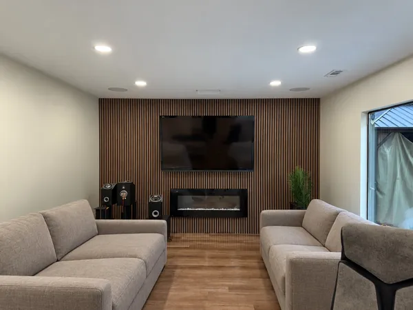Living room with a wood slat feature wall, wall-mounted TV, linear electric fireplace and two sofas