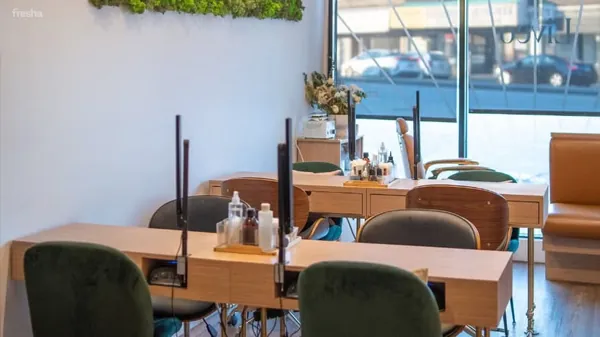 Manicure tables and green velvet chairs beside a window